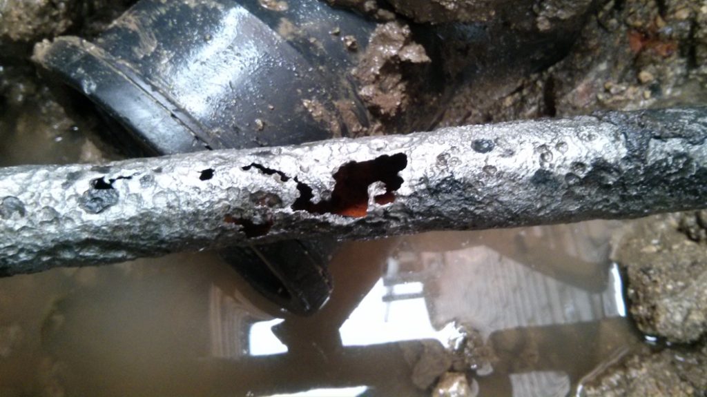A large crack and several holes in a 70mm malleable iron water supply pipe prior to being repaired with a SylWrap Pipe Repair Kit