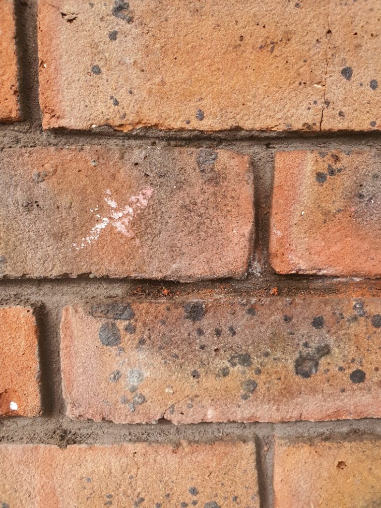 A section of brick missing a chunk because of lime blow undergoes a seamless repair and restoration using epoxy putty