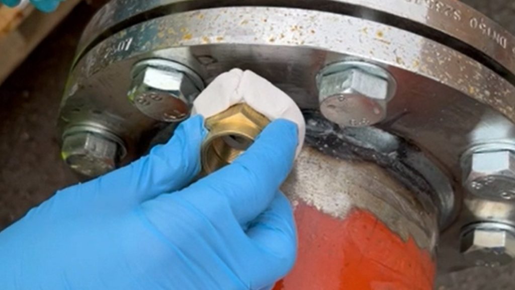 A leaking flange on a 150mm steel pipe undergoes repair by bonding a valve using underwater epoxy putty