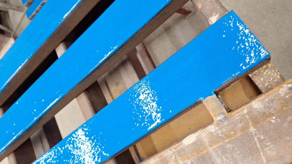 Metal pallets in a landscaping materials supplier warehouse are coated with Ceramic Brushable Epoxy to repair them after impact and abrasion damage