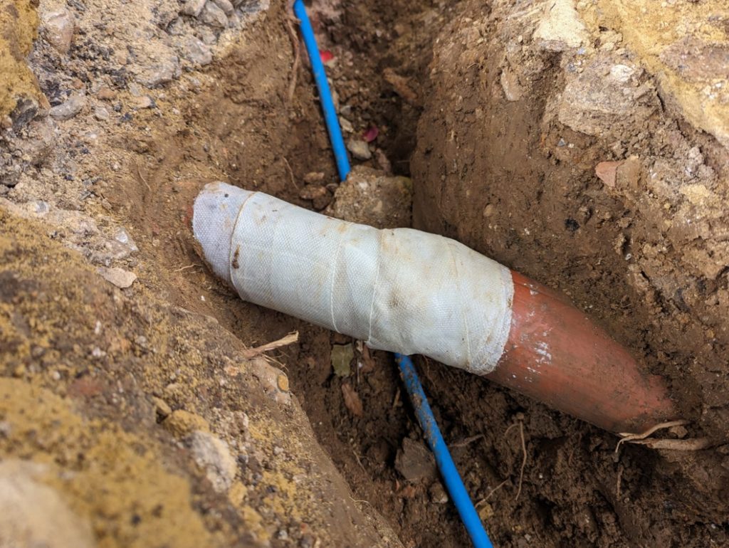 SylWrap HD Pipe Repair Bandage applied to an underground clay drainage pipe to reinforce the line after it cracked