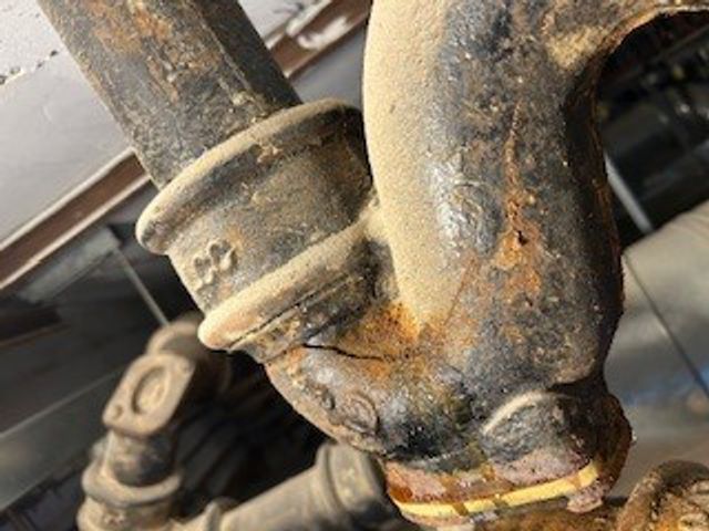 Hairline crack in a cast iron pipe U-bend through which wastewater was leaking at a UK hospital before undergoing repair