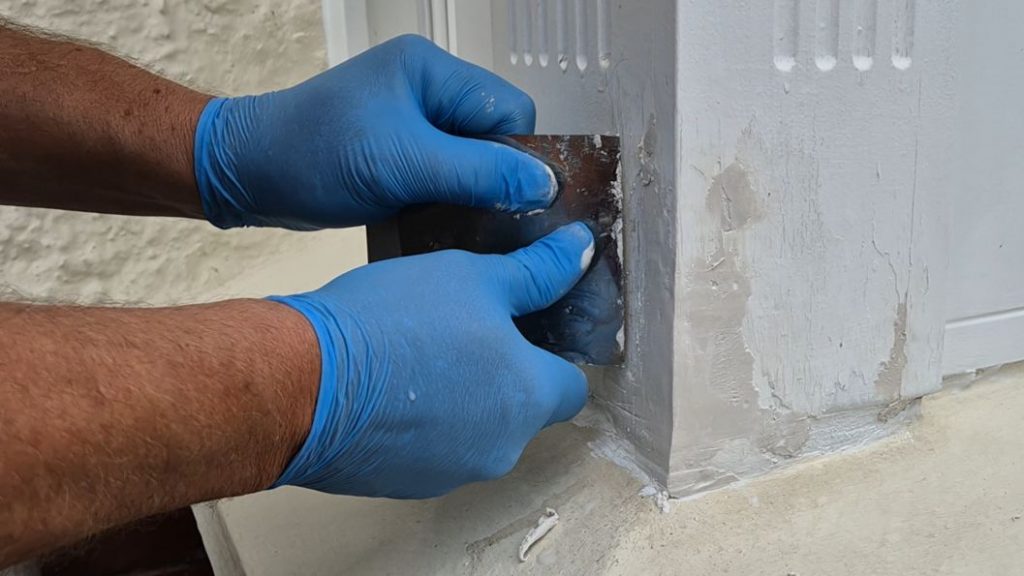Epoxy putty smoothed off with a metal spreader during the repair of a rotted bay sash window frame