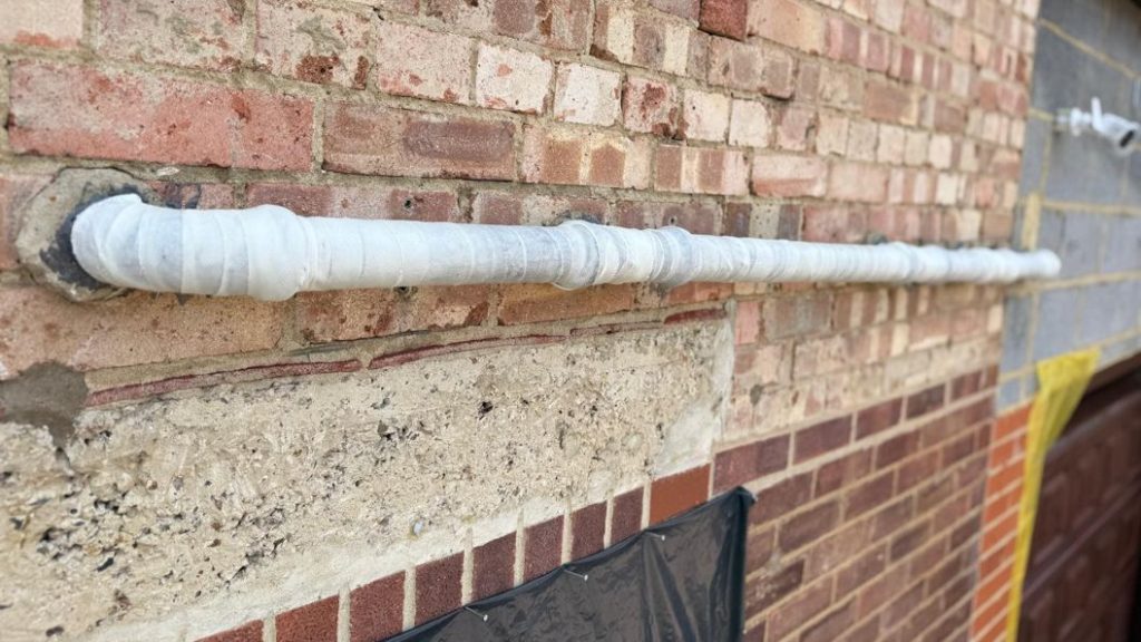 SylWrap HD Pipe Repair Bandaged applied along a 2-metre section of external plastic waste pipe, strengthening the 35-year-old line